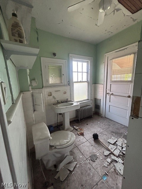 bathroom with tile walls, tile floors, radiator heating unit, and toilet