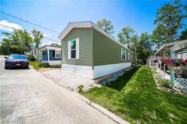 view of home's exterior with a storage unit, a lawn, and an outbuilding