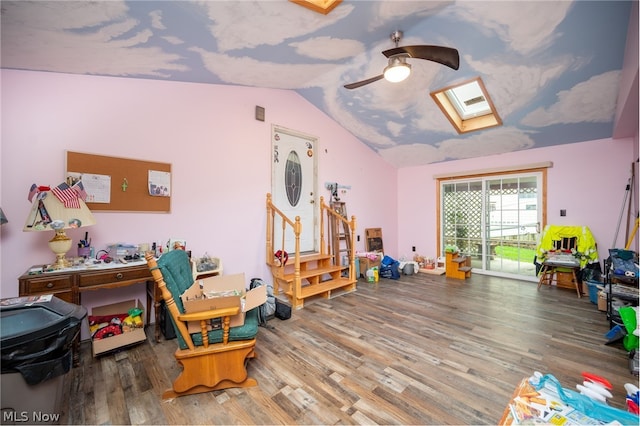 recreation room with ceiling fan, hardwood / wood-style flooring, and vaulted ceiling with skylight