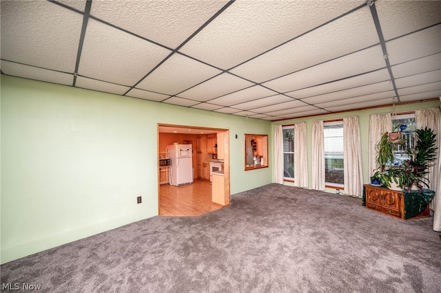 unfurnished living room with carpet flooring and a drop ceiling