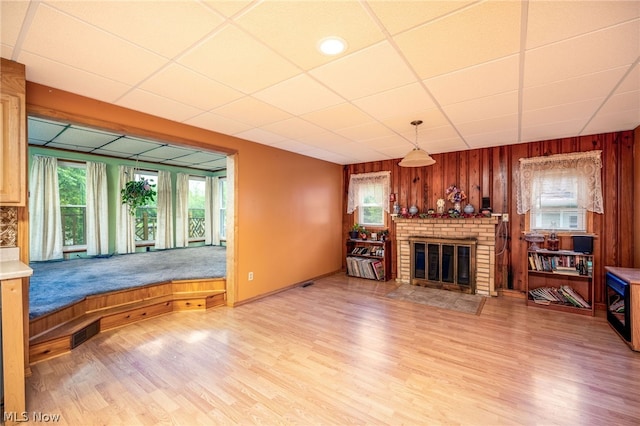 living room featuring wooden walls, hardwood / wood-style floors, a wealth of natural light, and a paneled ceiling