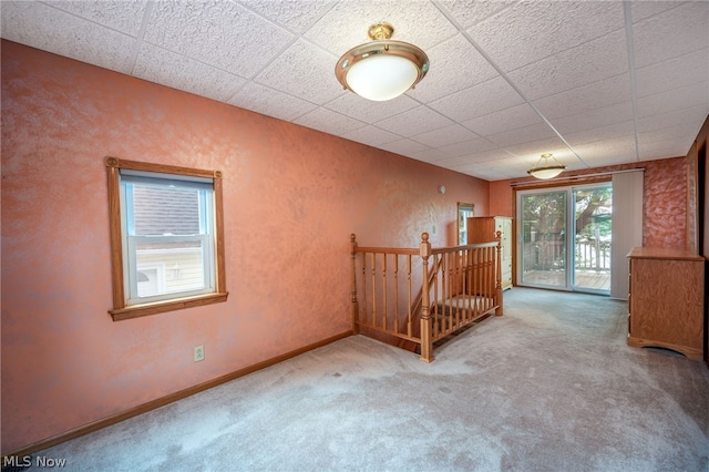 carpeted empty room featuring a paneled ceiling