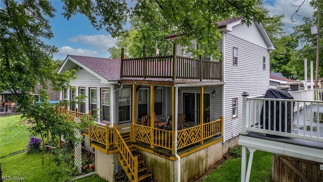 rear view of house with a balcony and a lawn