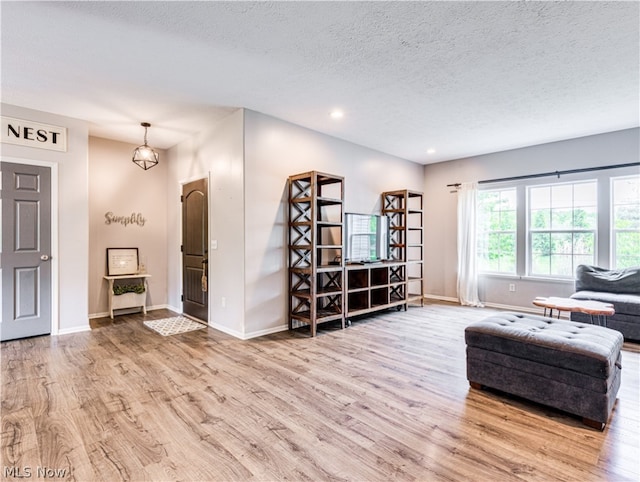 unfurnished room with light hardwood / wood-style flooring and a textured ceiling