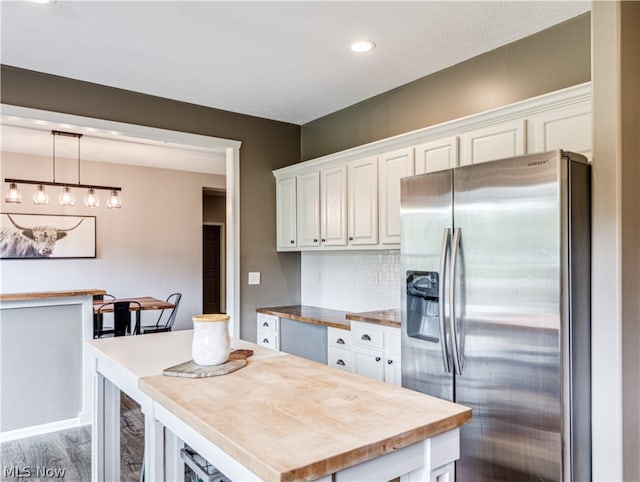 kitchen featuring stainless steel refrigerator with ice dispenser, decorative light fixtures, white cabinetry, and a kitchen island