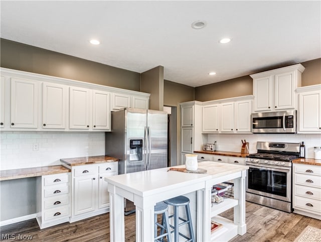 kitchen with wood-type flooring, stainless steel appliances, and white cabinetry