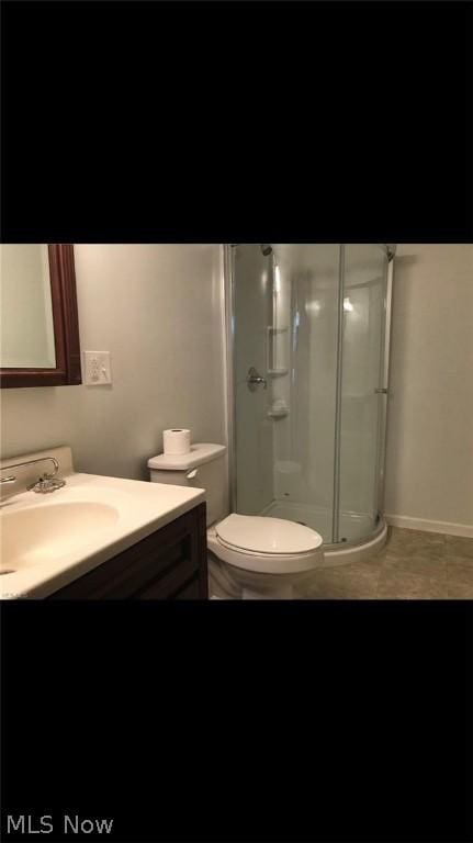 bathroom with tile patterned flooring, vanity, toilet, and walk in shower