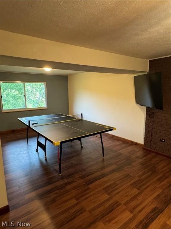 game room featuring dark wood-type flooring and a textured ceiling