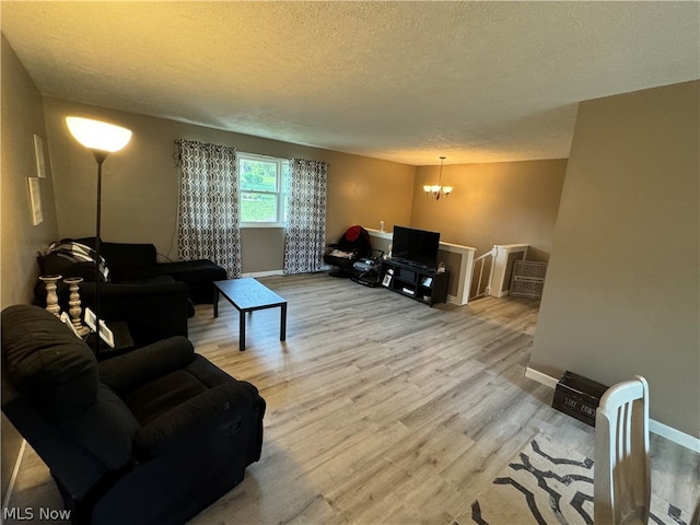 living room with a notable chandelier, a textured ceiling, and light wood-type flooring