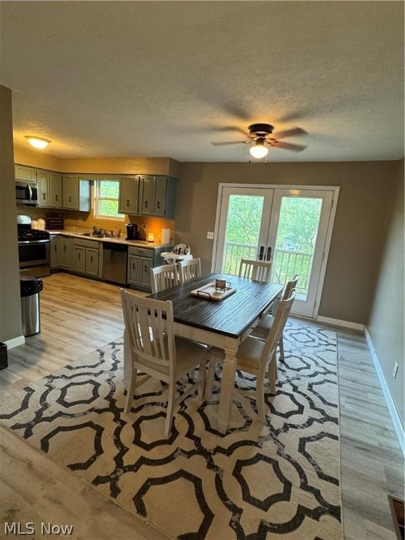 dining space with sink, light hardwood / wood-style flooring, french doors, and a textured ceiling