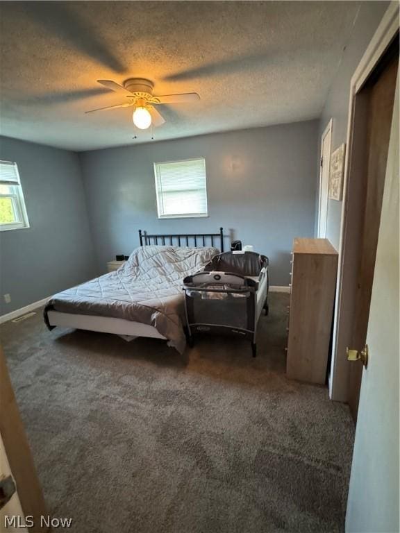 carpeted bedroom with ceiling fan and a textured ceiling