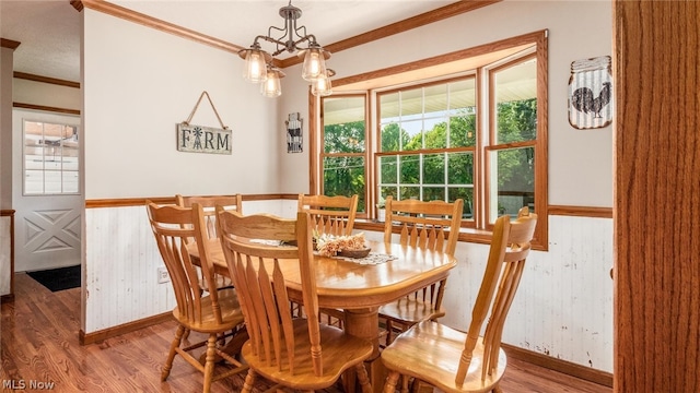 dining area featuring wood-type flooring, an inviting chandelier, and crown molding