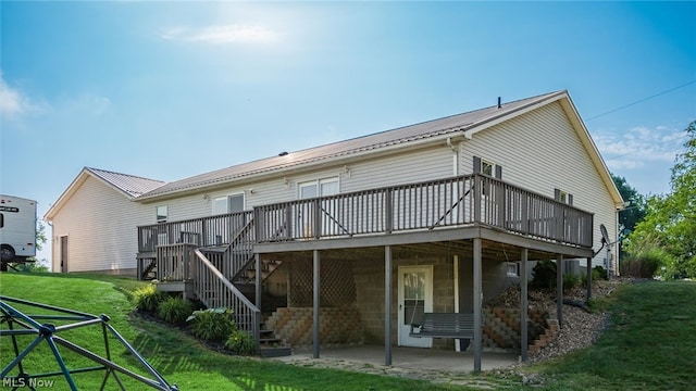 rear view of property with a deck, a patio area, and a lawn