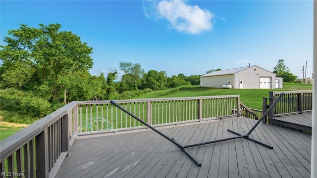 deck with a garage, an outdoor structure, and a lawn