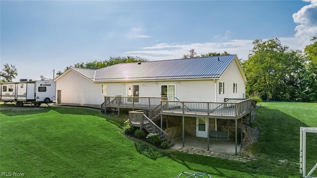 back of property featuring a wooden deck, a patio area, and a yard