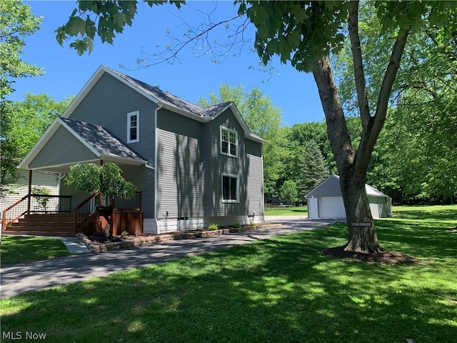 view of side of property featuring a lawn, an outbuilding, covered porch, and a garage