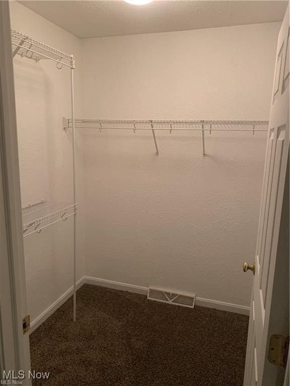 walk in closet with dark carpet