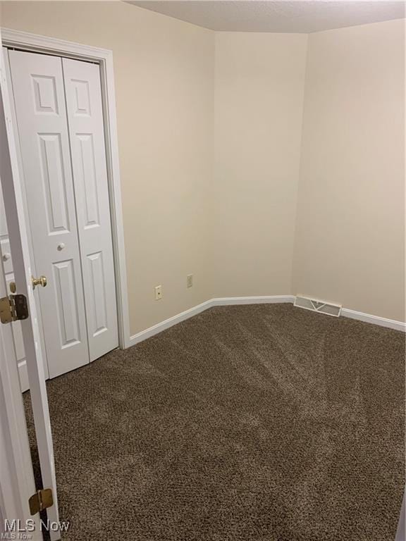 unfurnished room featuring dark carpet