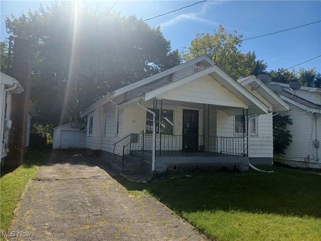 bungalow-style home with an outbuilding, a front lawn, and a garage