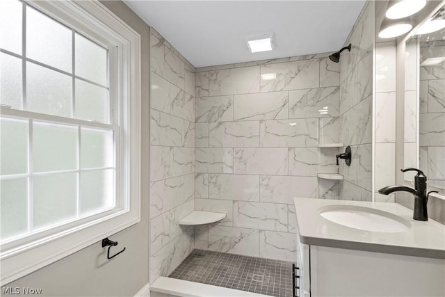 bathroom with a tile shower and vanity