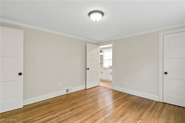 empty room with crown molding and hardwood / wood-style floors