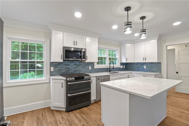 kitchen featuring light wood-type flooring, stainless steel appliances, sink, a center island, and white cabinetry