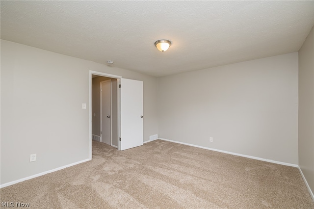 carpeted empty room with a textured ceiling