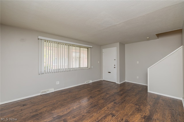 unfurnished room with dark hardwood / wood-style floors and a textured ceiling