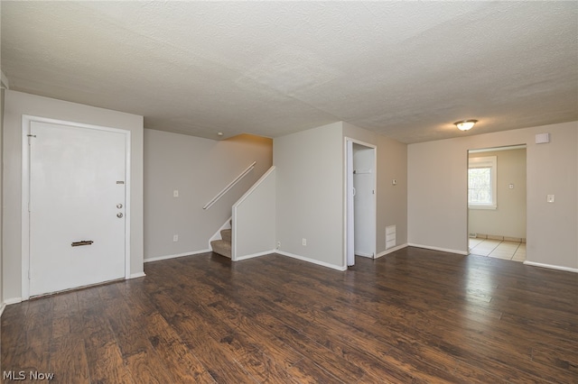 spare room with a textured ceiling and dark hardwood / wood-style floors