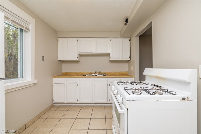 kitchen with white cabinetry, white gas range, sink, and light tile floors