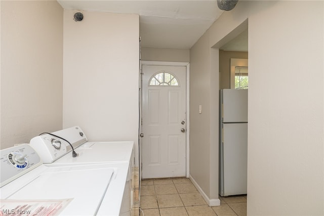 clothes washing area with washer and dryer and light tile flooring