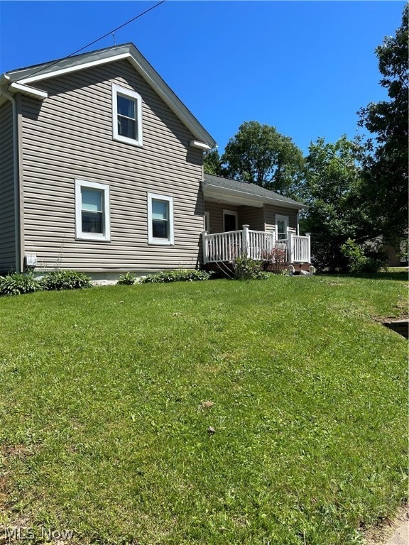 rear view of house featuring a yard and a deck