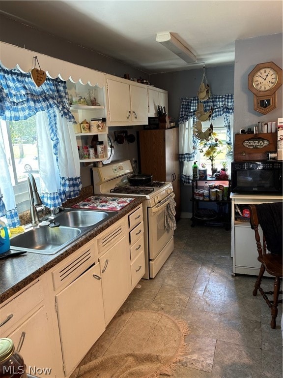 kitchen featuring white gas range oven, white cabinetry, and sink