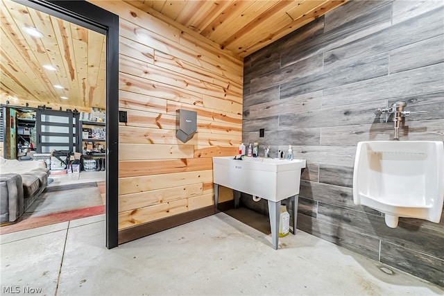 bathroom with wooden walls, concrete floors, and wooden ceiling