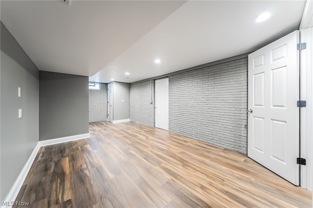 basement featuring brick wall and hardwood / wood-style floors