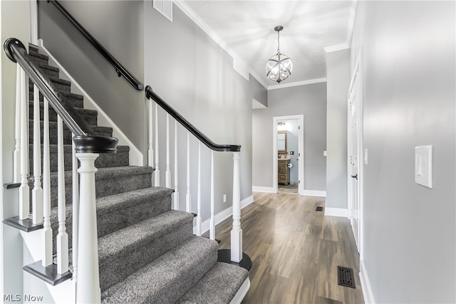 foyer with ornamental molding, hardwood / wood-style flooring, and a chandelier