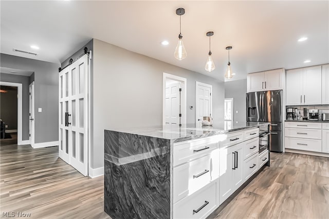 kitchen featuring a center island, white cabinetry, light stone countertops, hardwood / wood-style flooring, and stainless steel refrigerator with ice dispenser