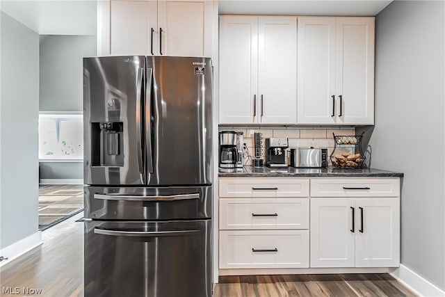 kitchen featuring tasteful backsplash, tile floors, stainless steel fridge, dark stone countertops, and white cabinets