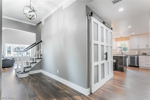 hall featuring dark hardwood / wood-style floors, a notable chandelier, crown molding, a barn door, and sink