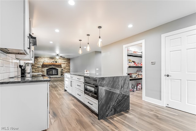 kitchen with light hardwood / wood-style floors, a fireplace, backsplash, ceiling fan, and white cabinetry