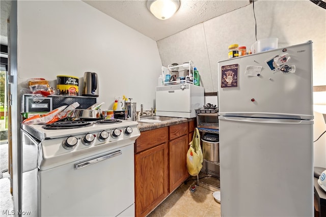 kitchen with vaulted ceiling, white appliances, and light tile floors