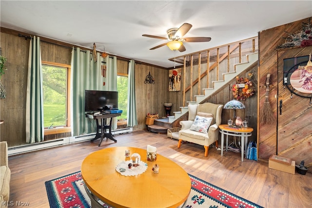 living room featuring a baseboard heating unit, wooden walls, ceiling fan, and hardwood / wood-style flooring