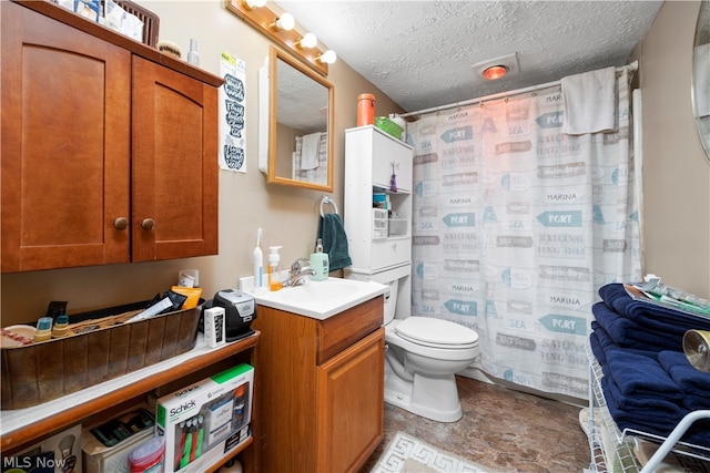 bathroom with tile flooring, oversized vanity, toilet, and a textured ceiling