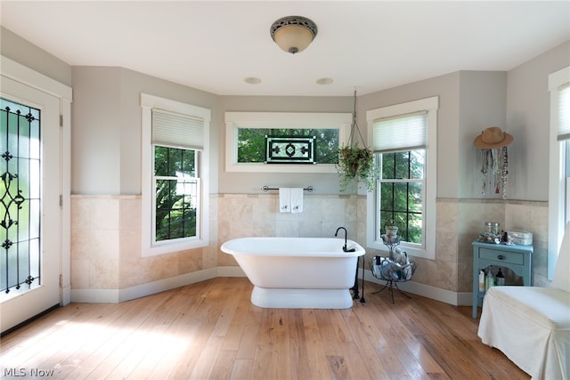 bathroom featuring tile walls, a healthy amount of sunlight, and hardwood / wood-style floors