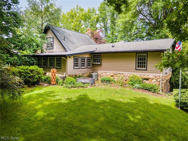 back of property featuring central AC unit and a yard