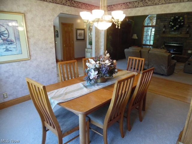 dining space featuring a large fireplace, wood-type flooring, and a chandelier