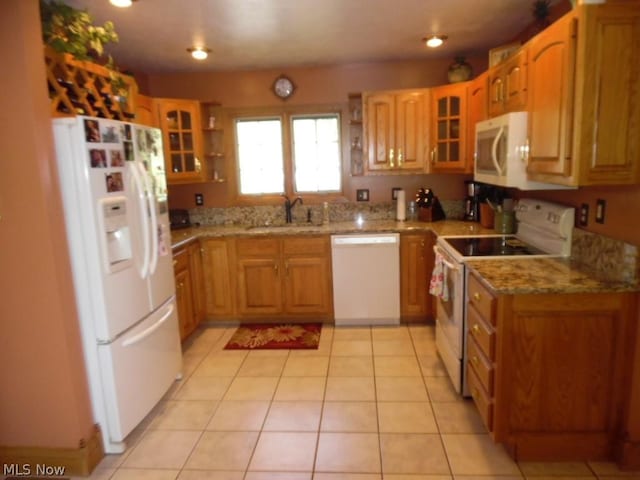 kitchen with light stone counters, white appliances, sink, and light tile patterned floors