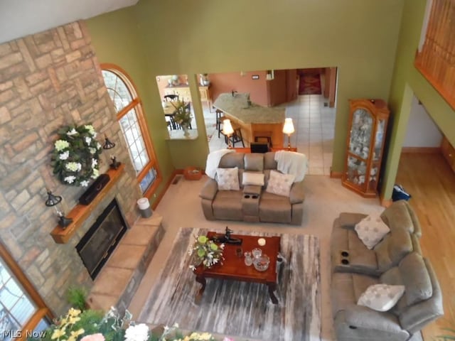 living room featuring a fireplace, a towering ceiling, and light wood-type flooring