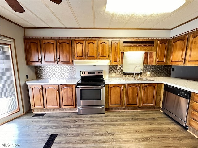 kitchen featuring crown molding, appliances with stainless steel finishes, hardwood / wood-style flooring, sink, and ceiling fan