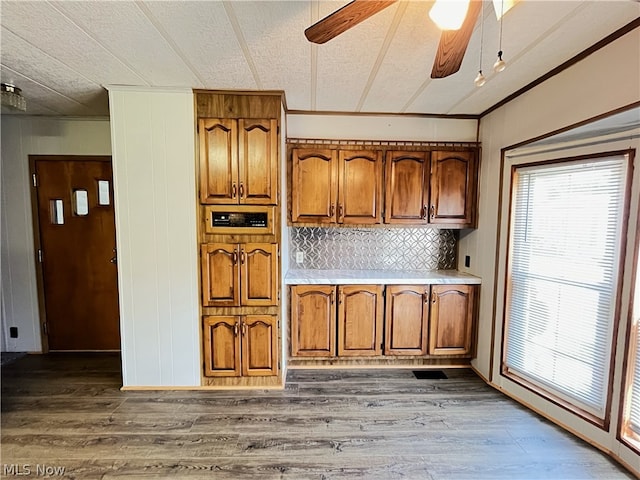 kitchen featuring backsplash, ceiling fan, hardwood / wood-style flooring, crown molding, and a textured ceiling